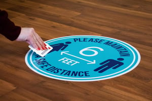 Person applying a walk on floor graphic to a wooden floor