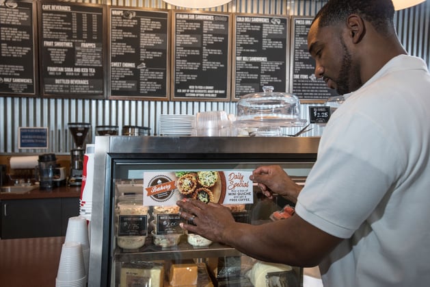 Man applying a ZTac vinyl graphic to a glass deli case.