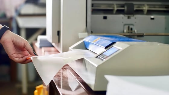 Person pulling  a piece of paper from a printer