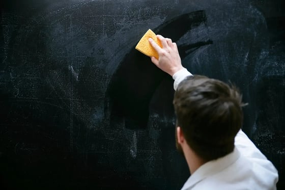 man cleaning a chalk board with a wet sponge