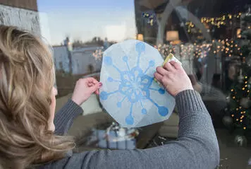 Woman applying a snowflake GMI vinyl window graphic