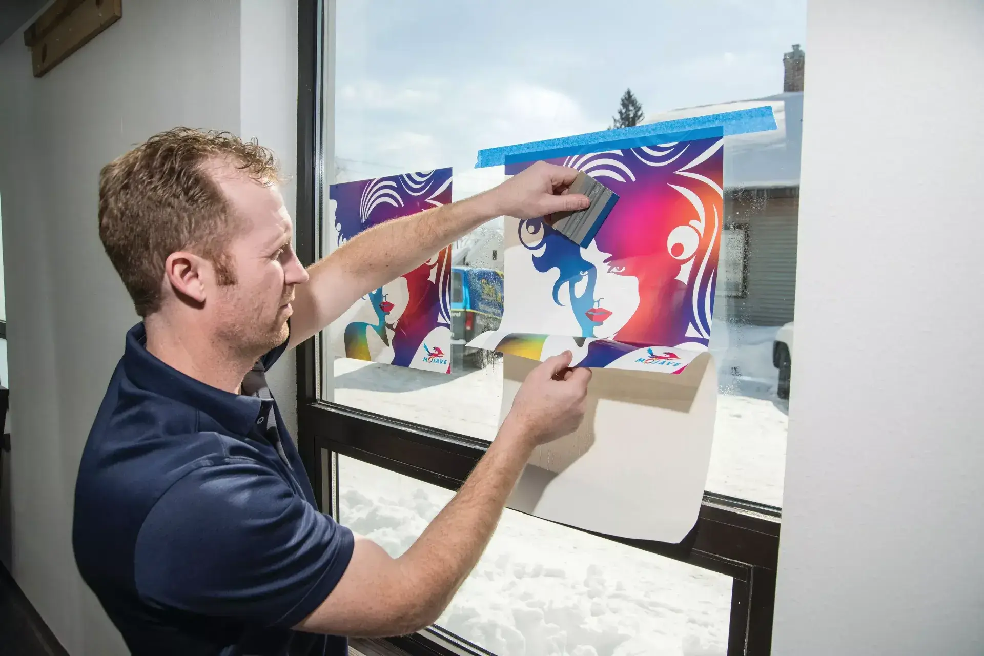 Man applying a vinyl window graphic to a window